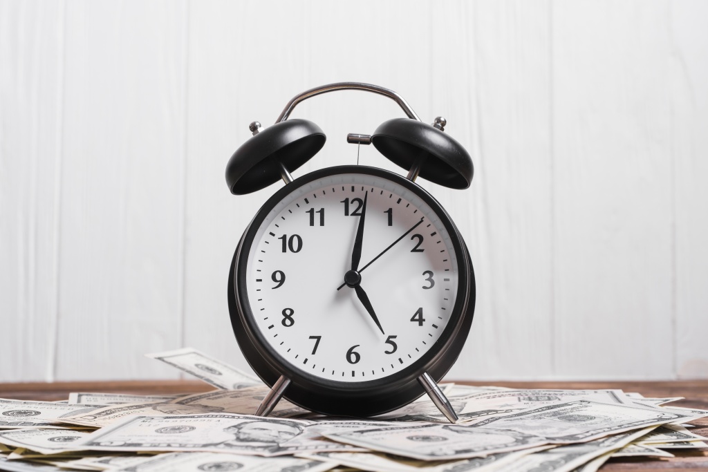 alarm-clock-us-dollar-currency-notes-wooden-desk-against-white-wall.jpg часы